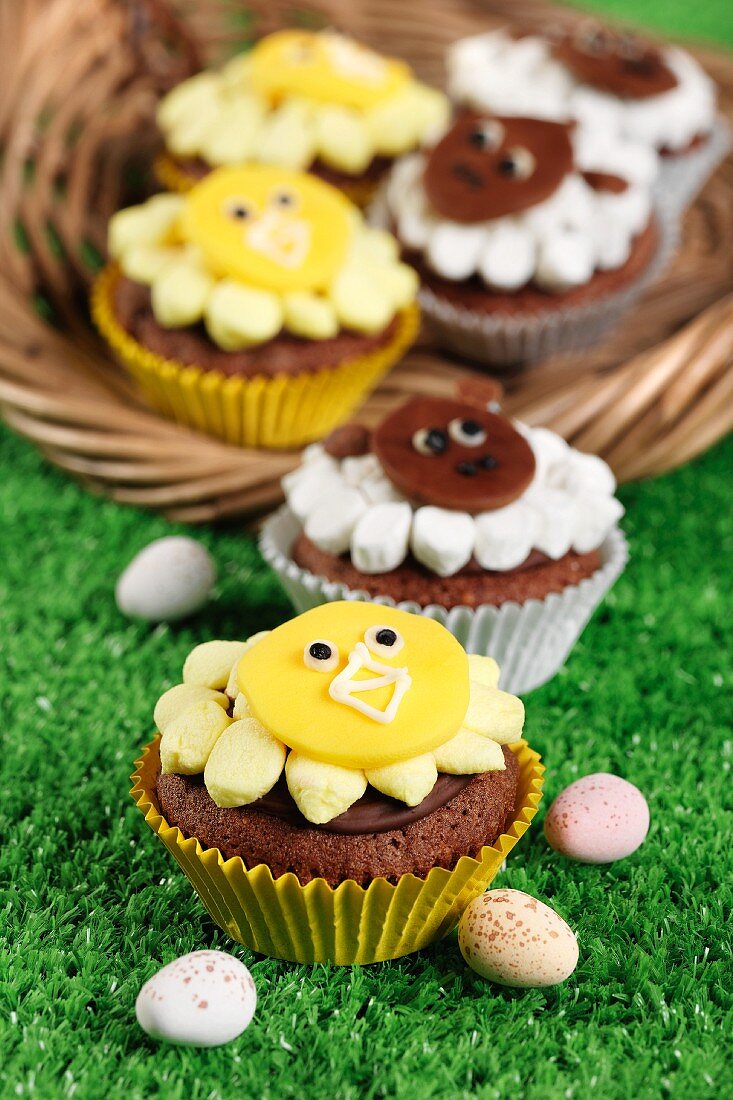 Easter animal themed cupcakes on grass and in a basket with mini easter eggs