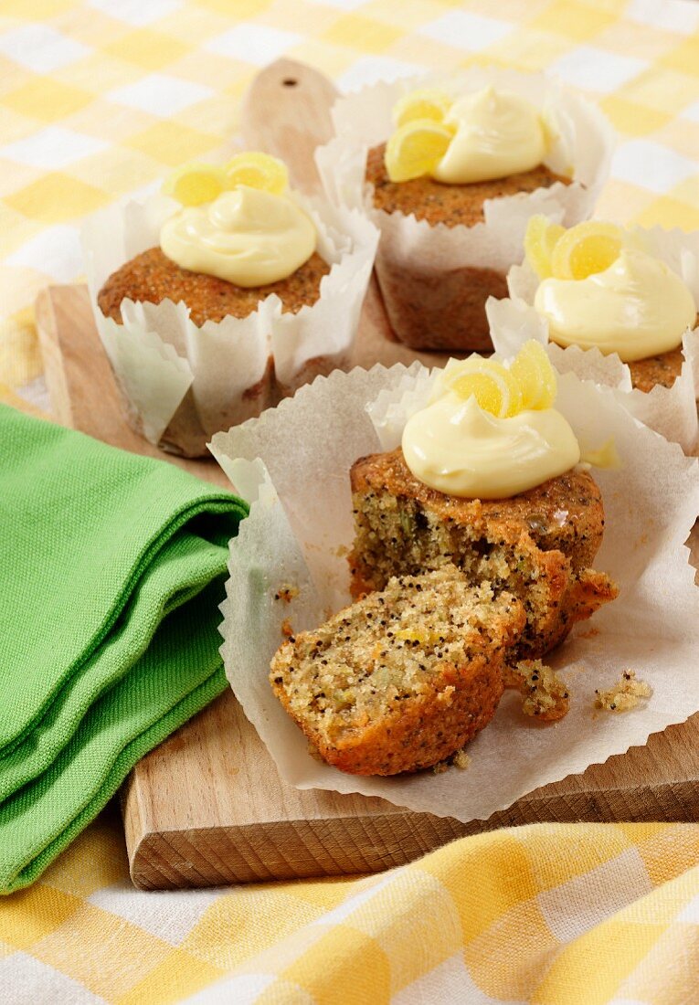 Several Seeded Lemon drizzle cupcakes in white paper cupcake cases on a wooden board