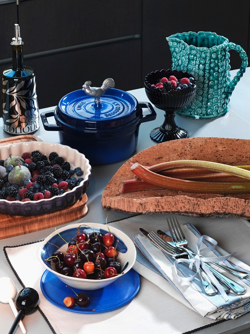 Cherries in a bowl, berries and figs in tart, rhubarb, crockery and cutlery