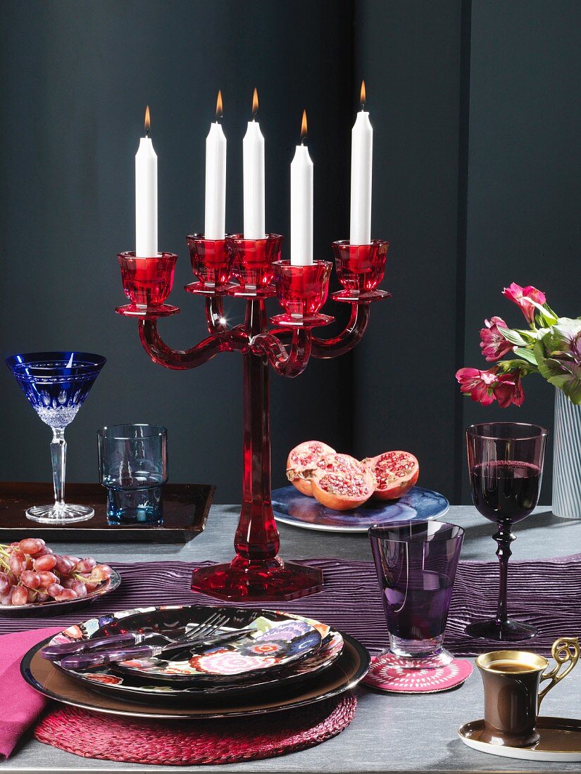 Geschirr, Kerzenleuchter, Obst, Wein und Kaffee auf Tisch