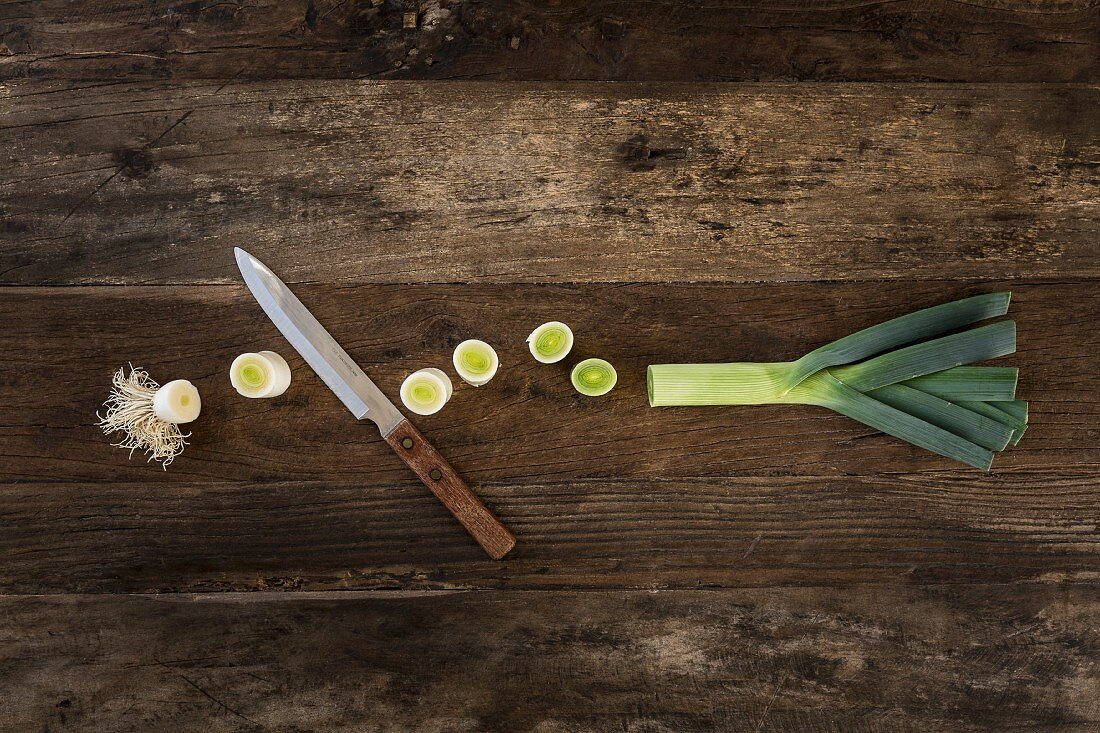 Leek cut into pieces with a knife on a wooden surface