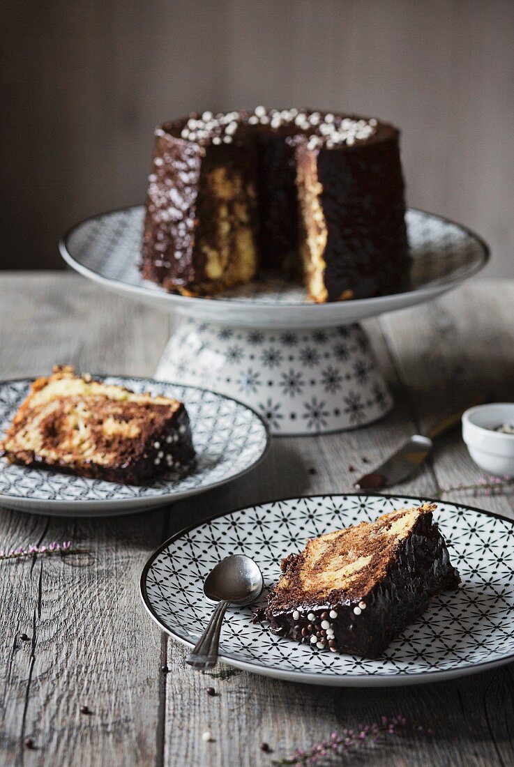 Marmor-Chiffon-Cake mit Schokoladenglasur auf grauem Holztisch, angeschnitten