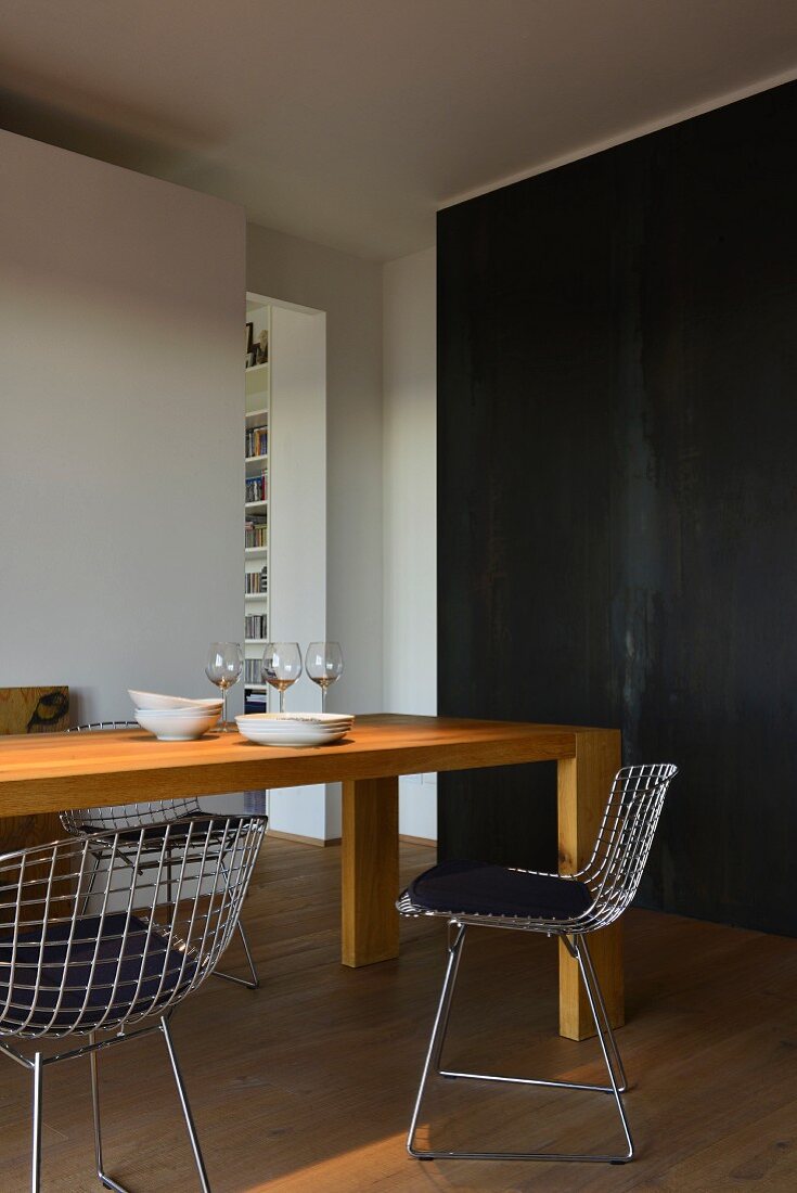 Solid oak table and metal chairs in front of black metal cladding
