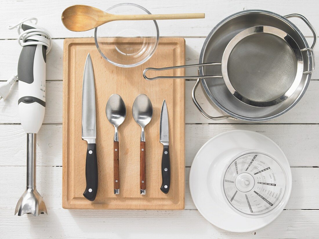 Various kitchen utensils: blender, cutlery, pot, strainer, measuring cup
