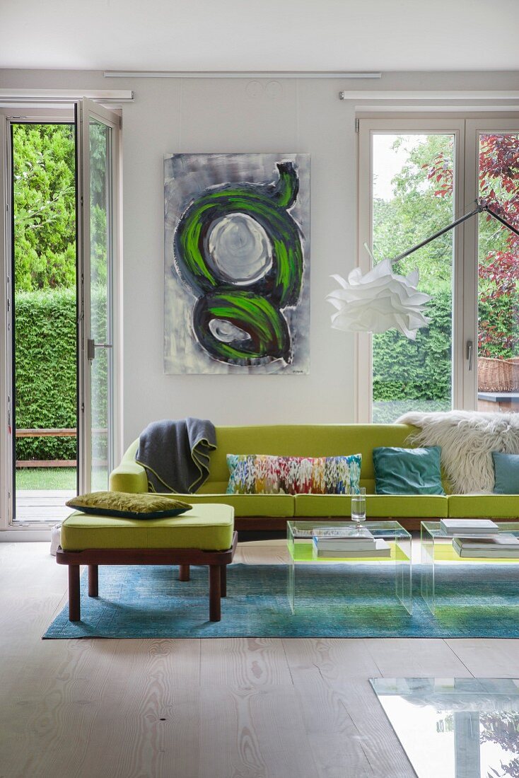 Green sofa on blue rug in front of floor-to-ceiling windows