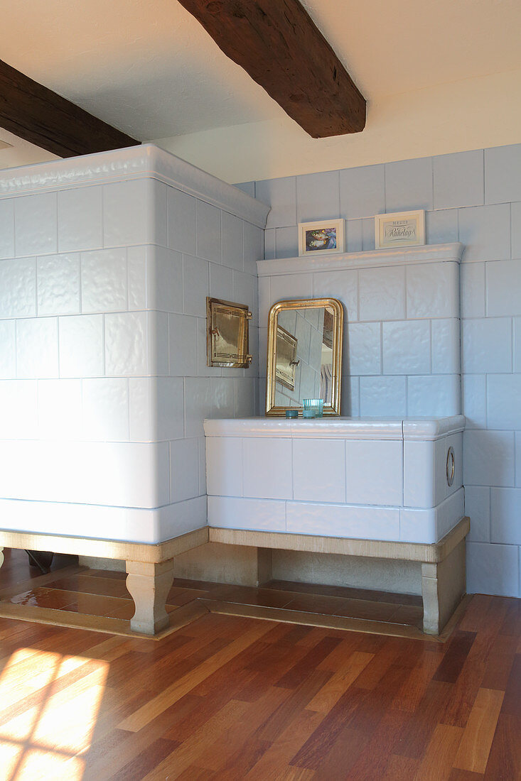 Gilt-framed mirror on traditional tiled stove