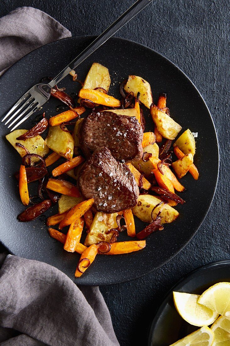 Pan-fried steaks on a bed of oven-baked vegetables and dates