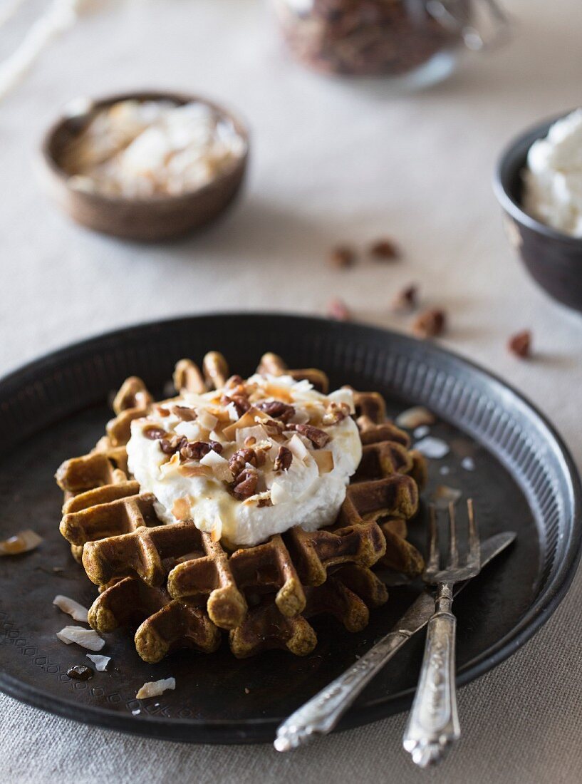 Spicy Pumpkin Waffles with Coconut Whipped Cream served on a dark color plate