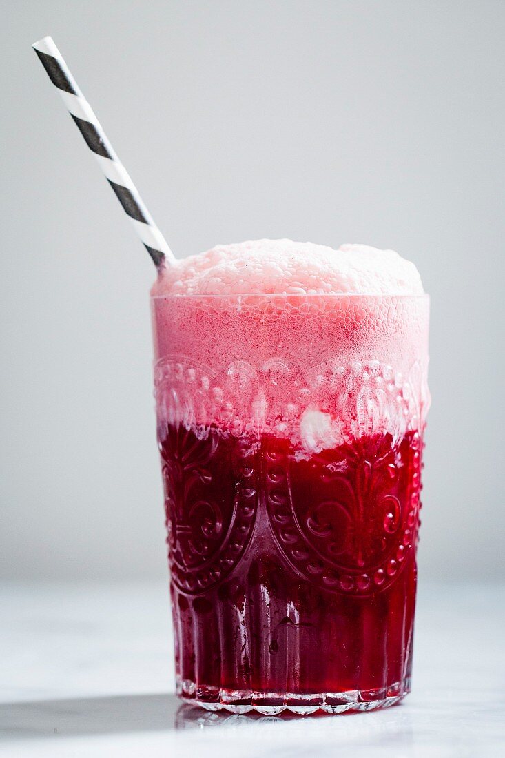 Hibiskus-Soda mit Strohhalm im Glas