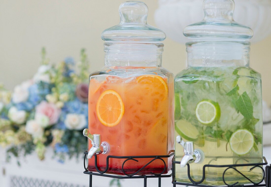 Orangensaft und Limettenwasser in Glasgefässen mit Deckel und Zapfhahn