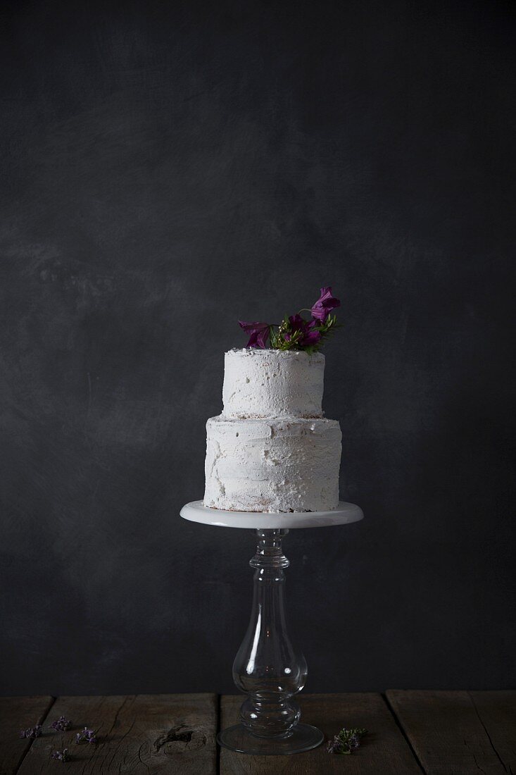 Zweistöckige Torte verziert mit Blüte auf Tortenständer