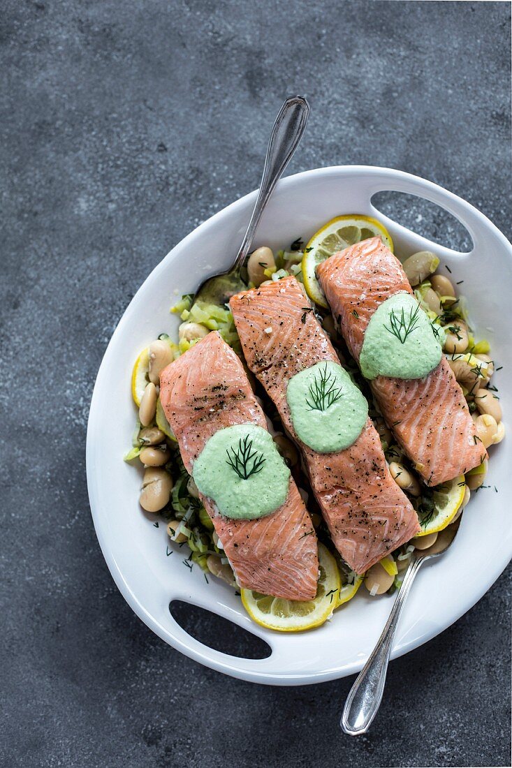 A plate white butter beans topped with oven baked salmon slices