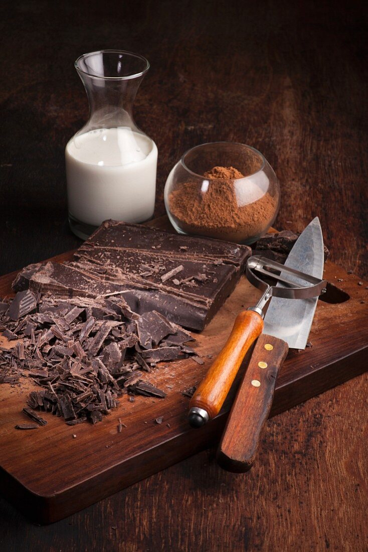 Dunkle Schokolade, Kakaopulver und Milch auf Holzuntergrund