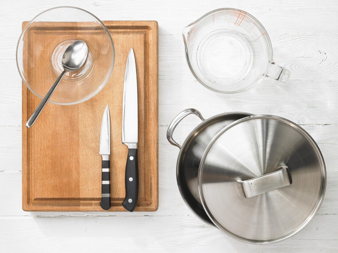 Various kitchen utensils: pot, measuring cup, knives, glass bowl, spoon