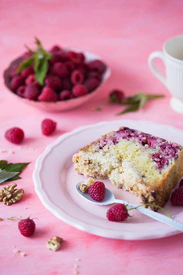 A slice of a cake with raspberries on a pink plate