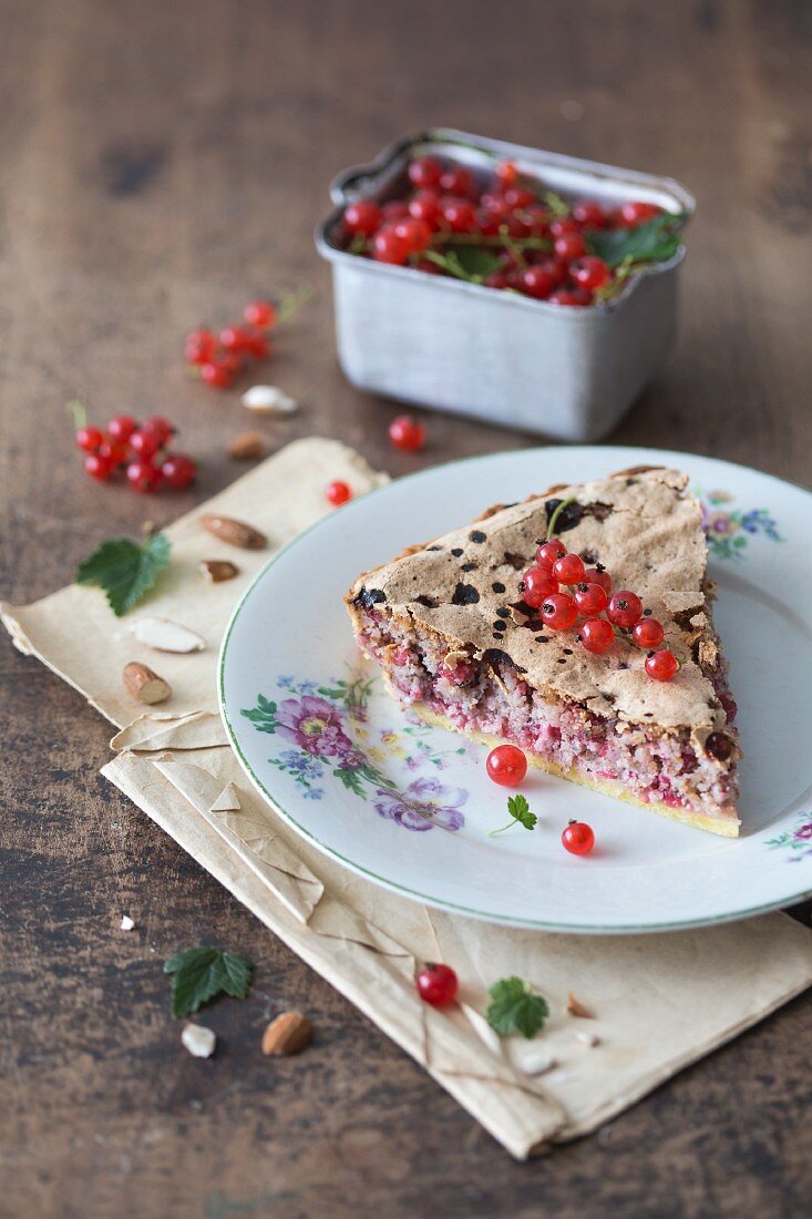 Ein Stück Mandel-Johannisbeer-Tarte auf geblümtem Teller