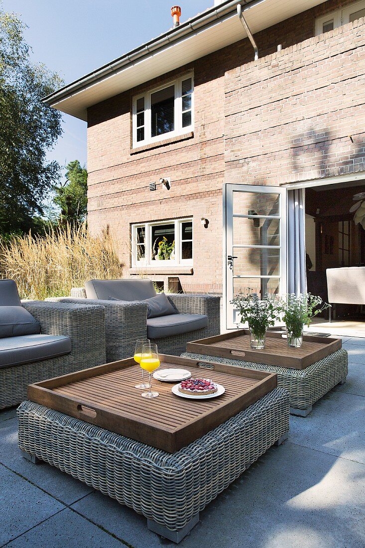 Loungesessel und Tabletttische auf der Terrasse vor dem Backsteinhaus