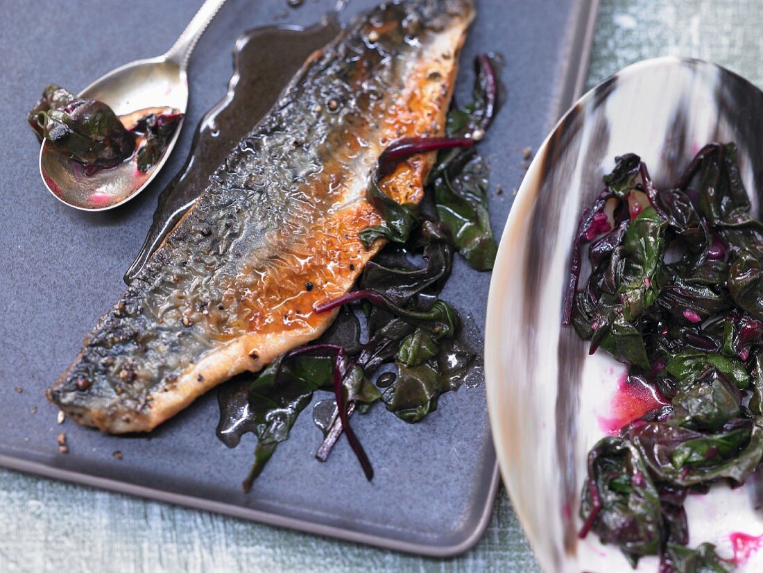 Fried mackerel fillets with red wine sauce on roasted beetroot leaves