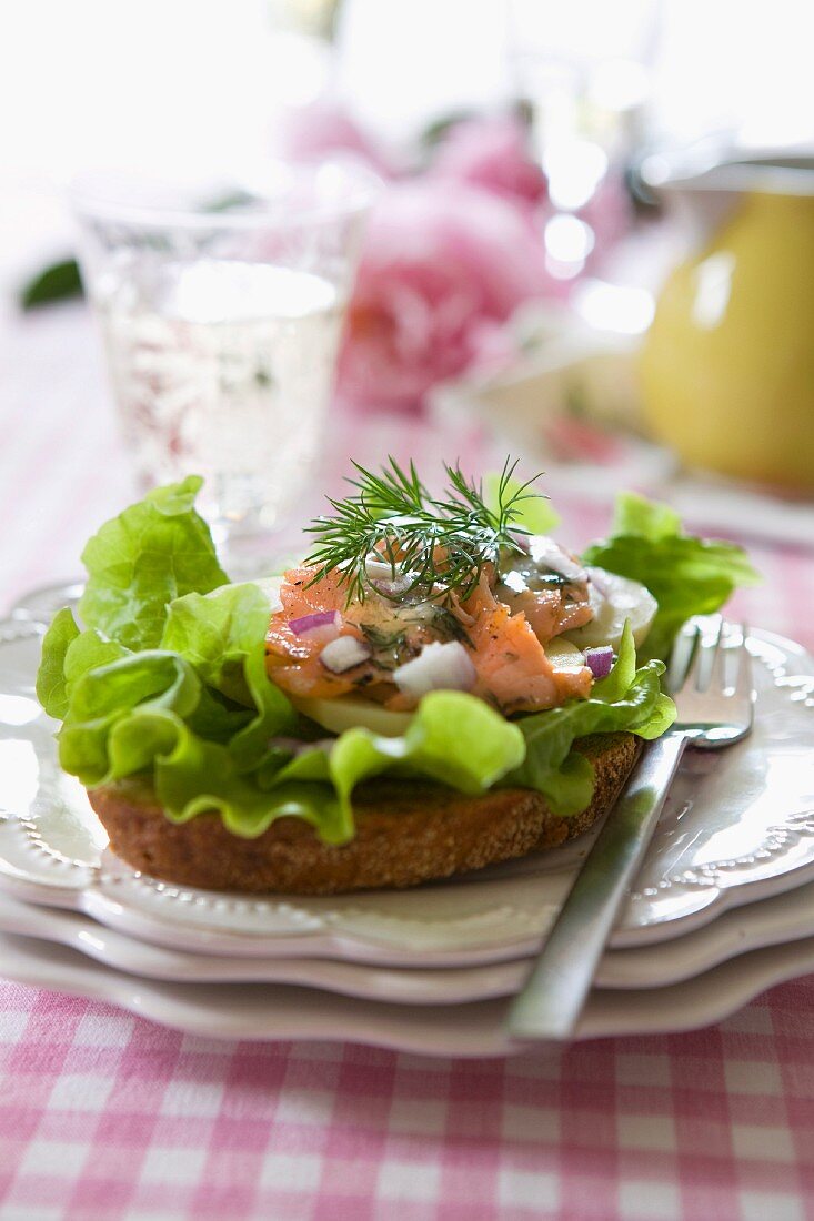 Salmon sandwich with egg, letuce, red onion, dill and a glass of white wine