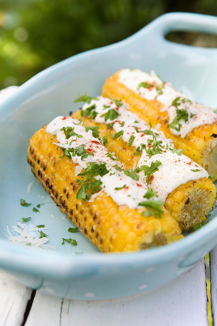 Grilled corn-cob with sauce and fresh herbs