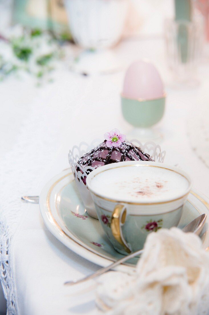 Cappuccino in Goldrandtasse und Cupcake auf Goldrandteller