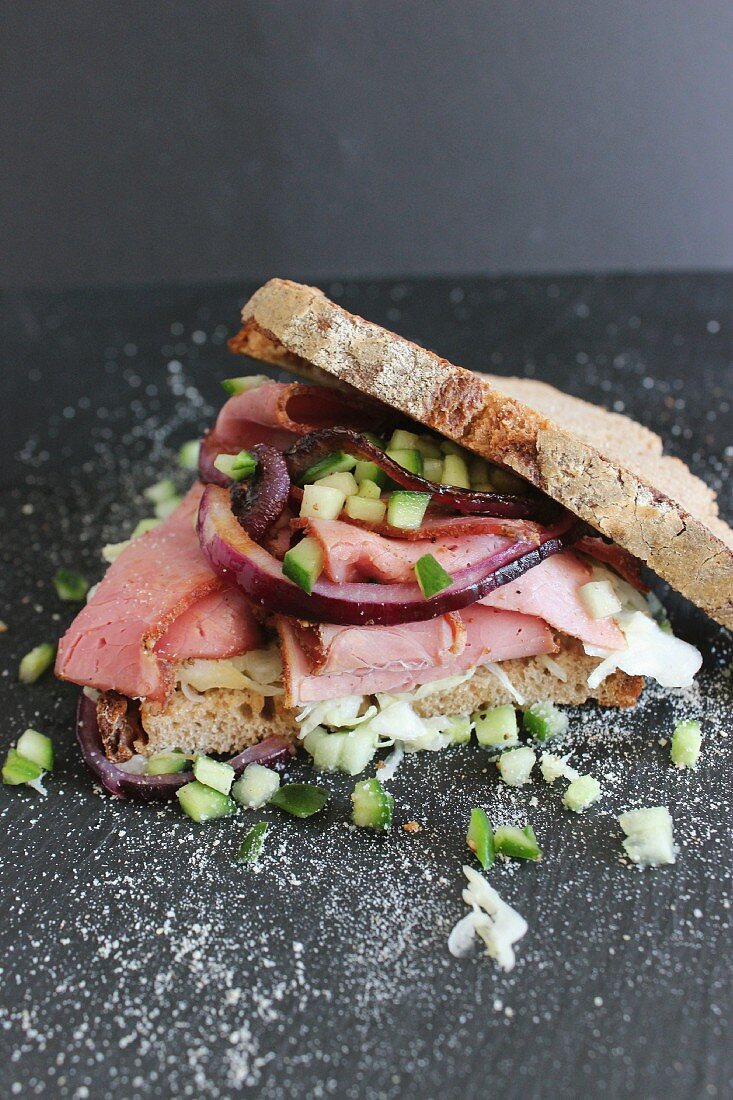 A pastrami sandwich with pieces of cucumber