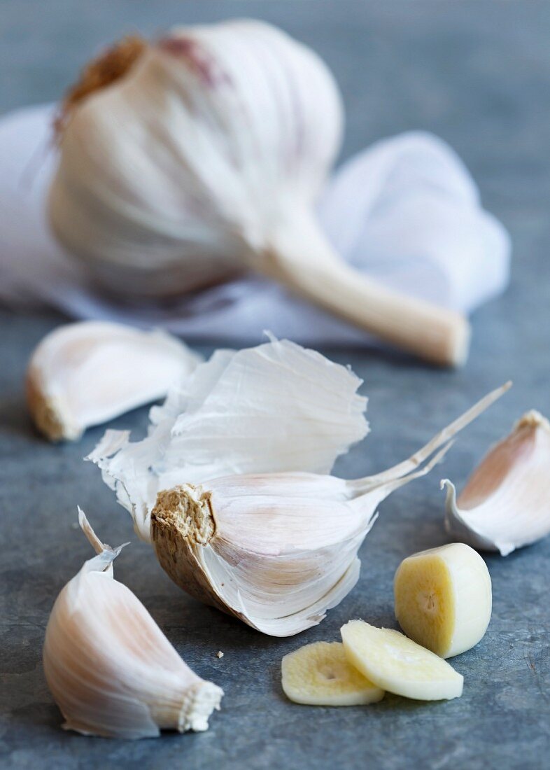 Cut up clove of purple stripe garlic with unpeeled cloves lying on a blue-grey sheet metal