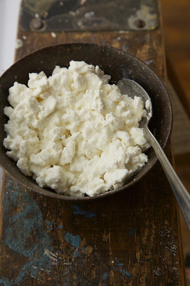 Grobkörniger Hüttenkäse in Schale mit Löffel