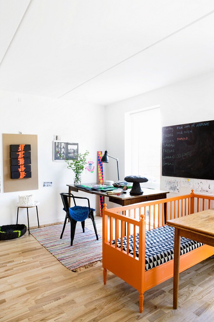 Old orange bench with patterned seat cushion next to desk