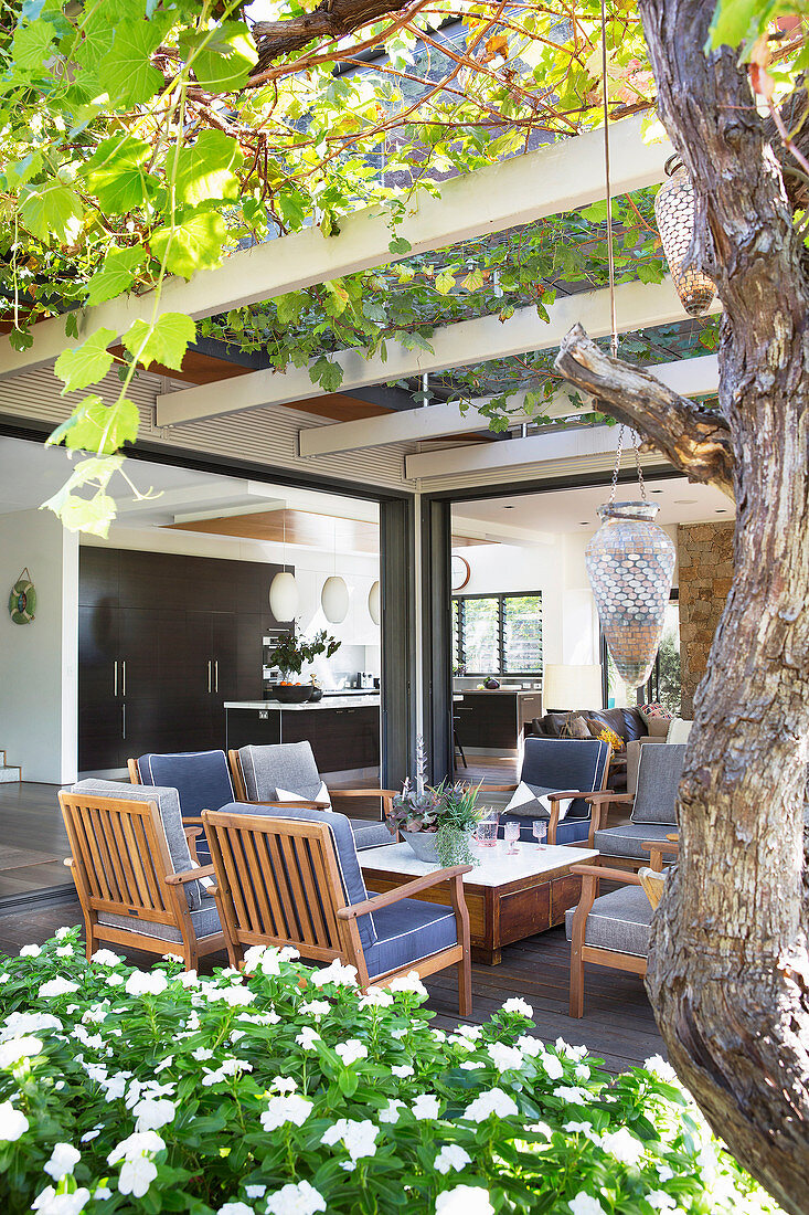 Upholstered wooden armchairs under the overgrown pergola