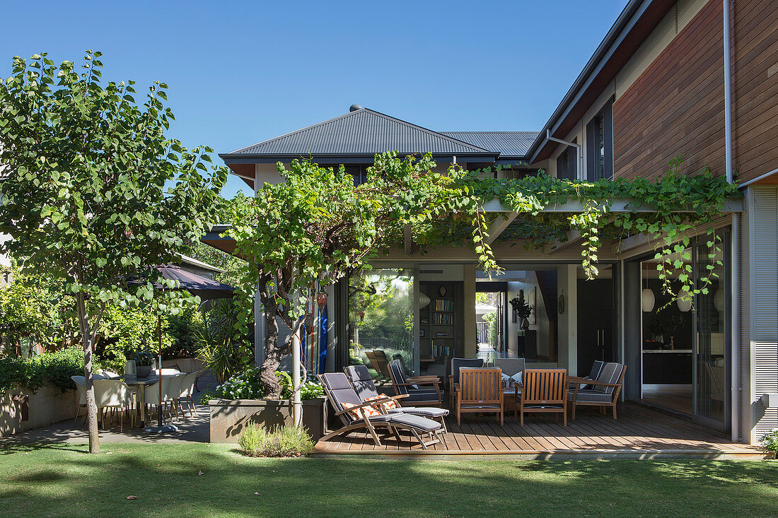 View from the garden onto the pergola with seating, overgrown with wine