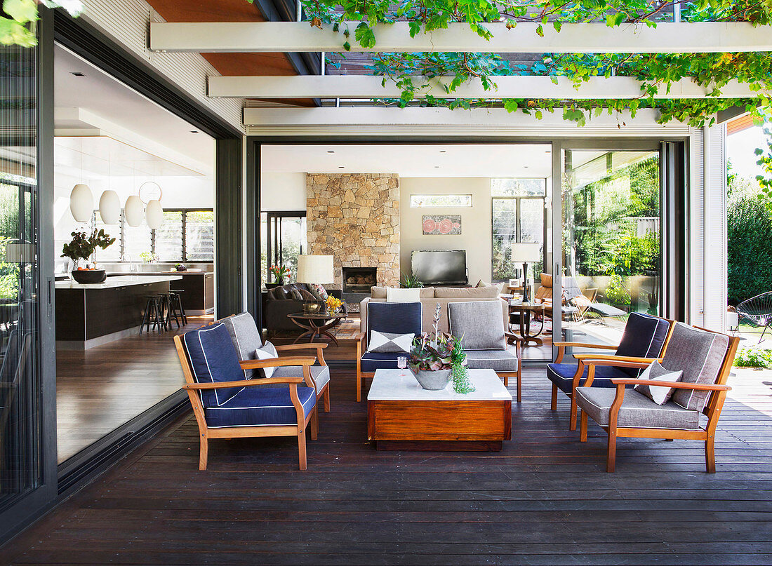 Upholstered wooden armchairs under the overgrown pergola