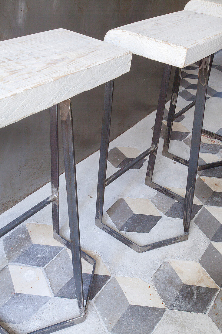 Rustic barstools made of metal and rough wood on old tiled floor