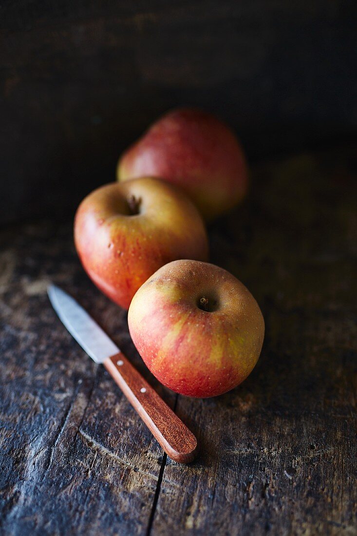 Drei Boskop-Äpfel mit Obstmesser