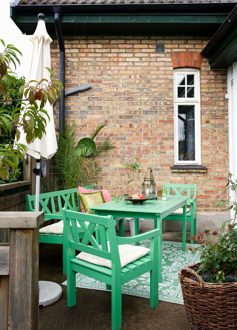 Grüne Gartenmöbel auf der Terrasse vor dem Backsteinhaus