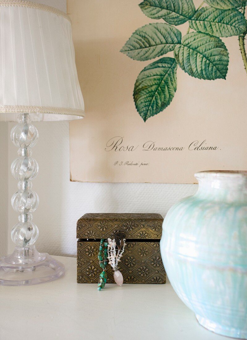 Vase, lamp and jewellery box below botanical illustration on poster