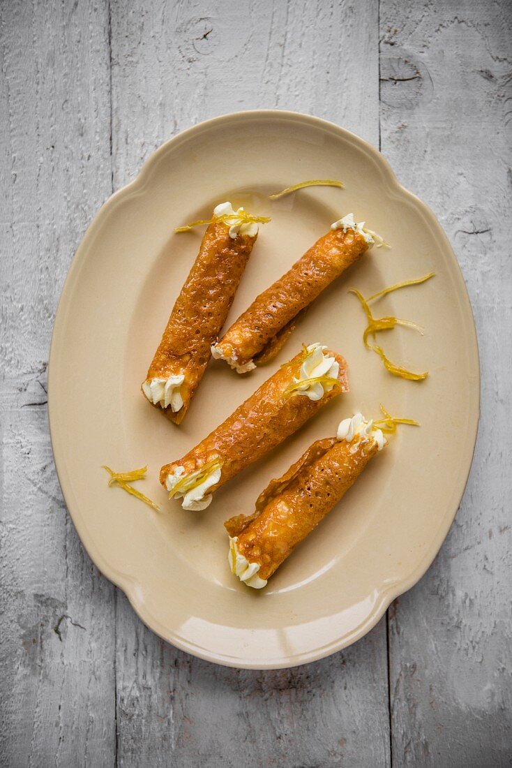 Brandy snap tuilles with lemon cream on aplate, viewfrom above.