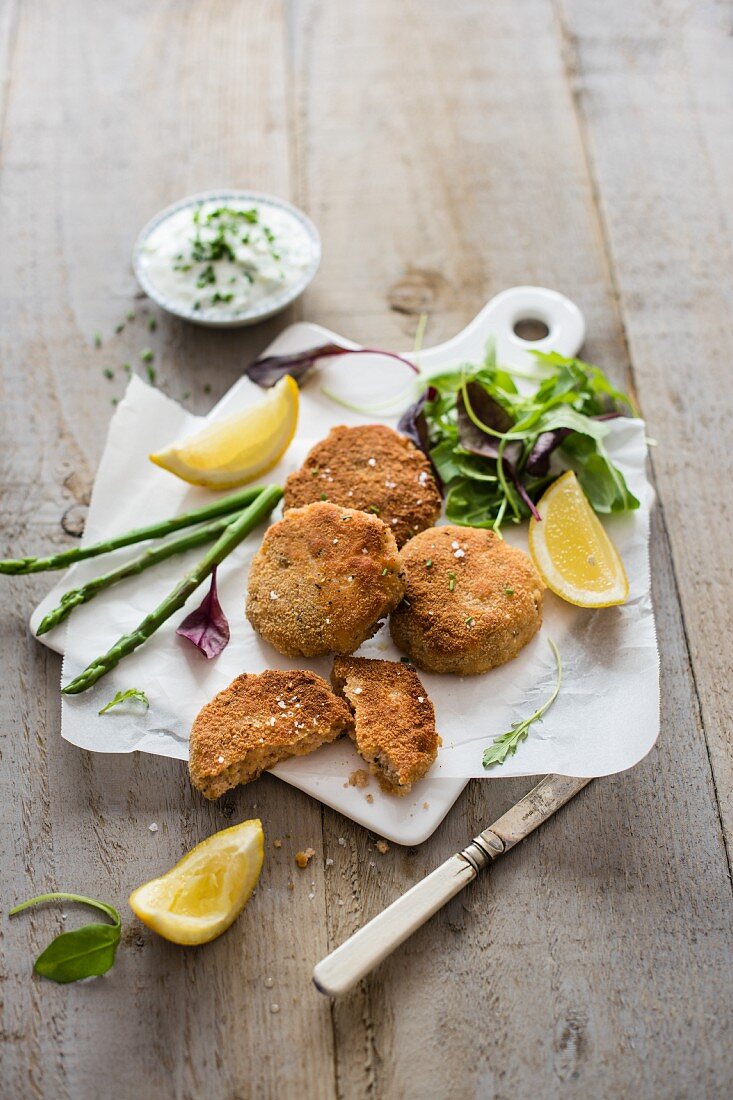 Salmon fishcakes with cucumber, yoghurt and chive dip, fresh salad, asparagus and lemon wedges