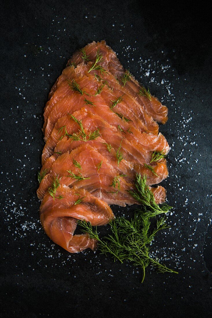 Slices of smoked salmon with sea salt flakes and dill