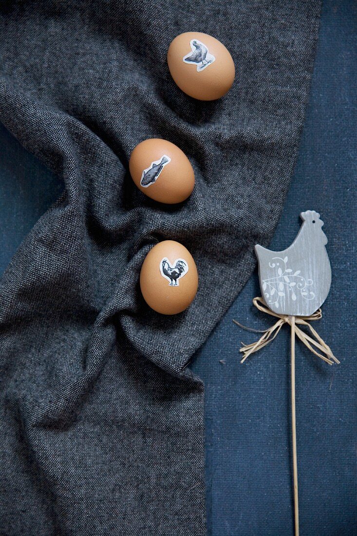 Easter eggs decorated with animal stickers next to hen ornament