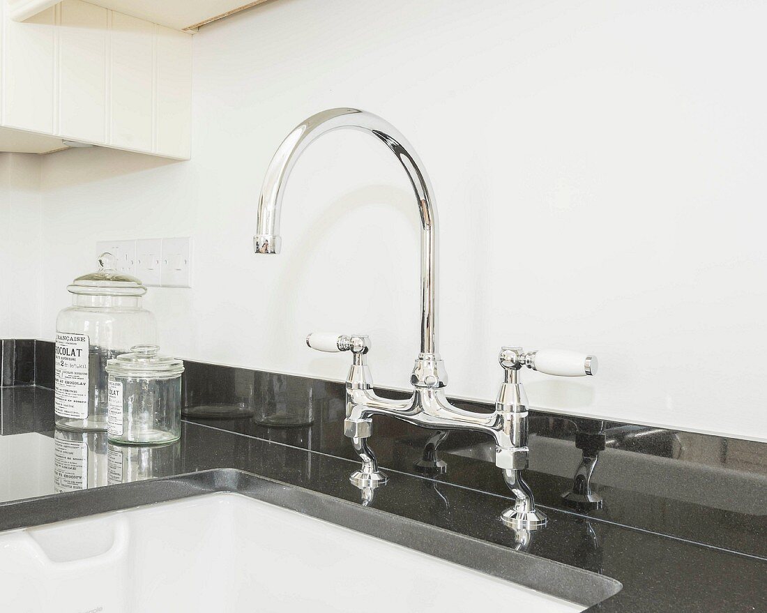 A mixer tap on a glossy black granite kitchen worktop