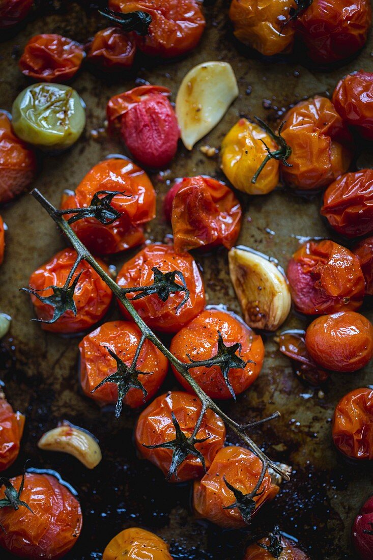 Oven-roasted tomatoes and garlic on a baking tray (seen from above)