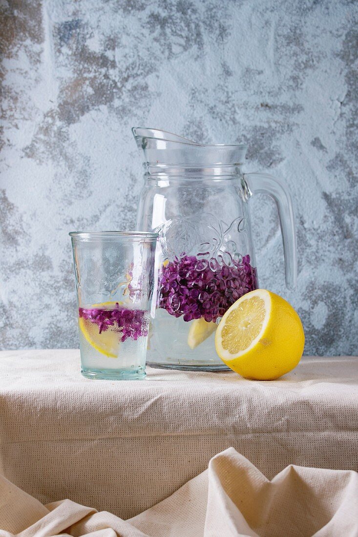 Fliederblütenlimonade mit Zitronen in Glas und Krug