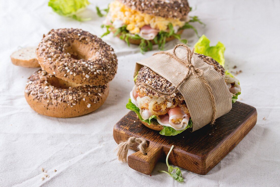 Whole Grain bagels with scrambled eggs, pea sprout, fried onions and prosciutto ham