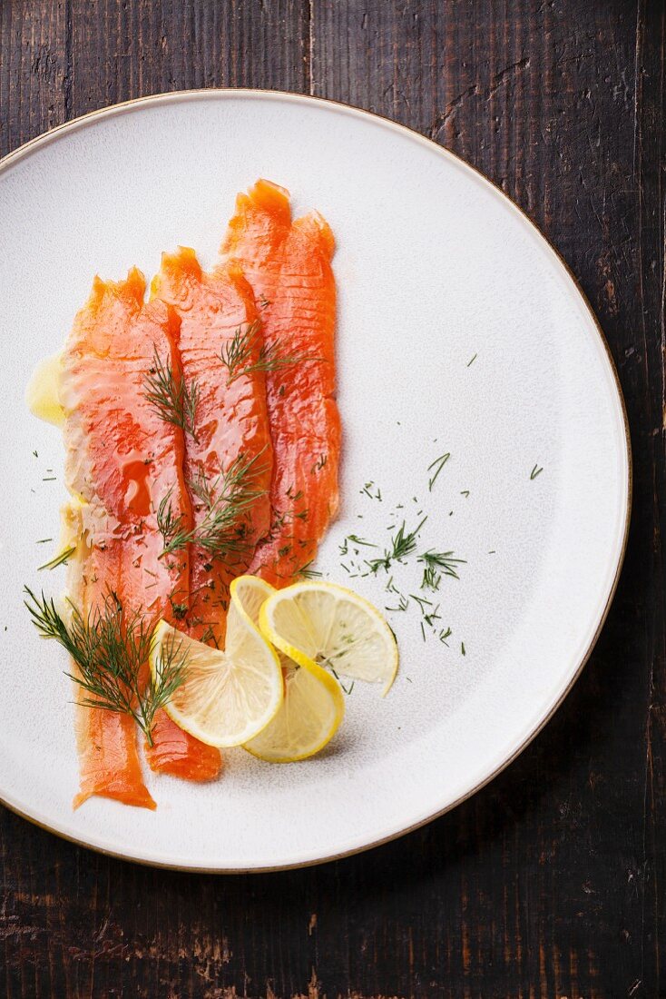 Geräucherter Lachs mit Dill und Zitrone auf weißem Teller