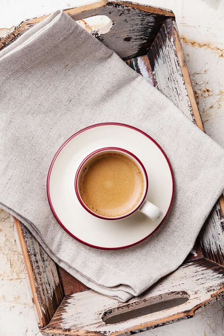 Eine Tasse Kaffee auf Leinentuch und Vintage-Holztablett (Aufsicht)