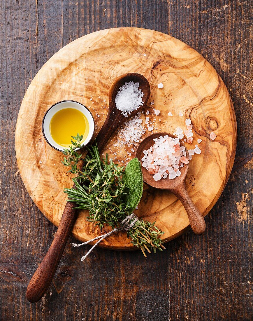 Different types of food coarse Salt in wooden spoons on dark background