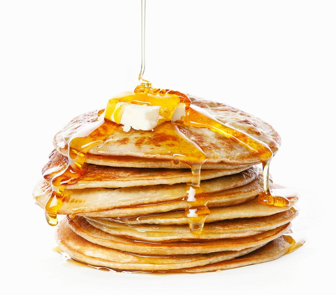 Honig fliesst auf Stapel Pancakes mit Butter (Nahaufnahme)