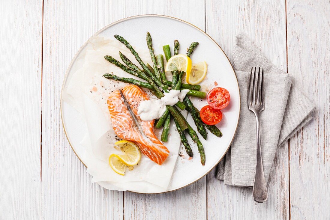 Grilled salmon with asparagus on white wooden background