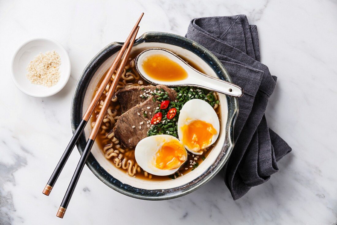Miso Ramen Asian noodles with beef and egg in bowl on white marble background